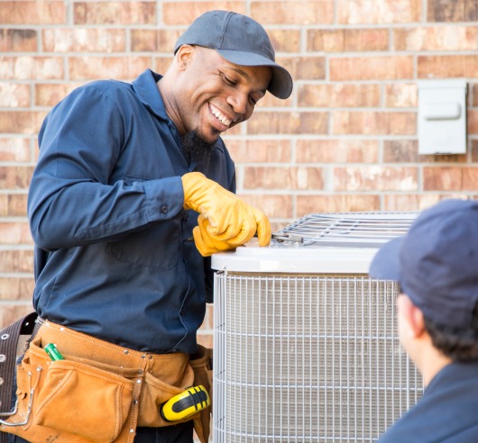 A man smiles as he tries to pry open an air conditioning unit.